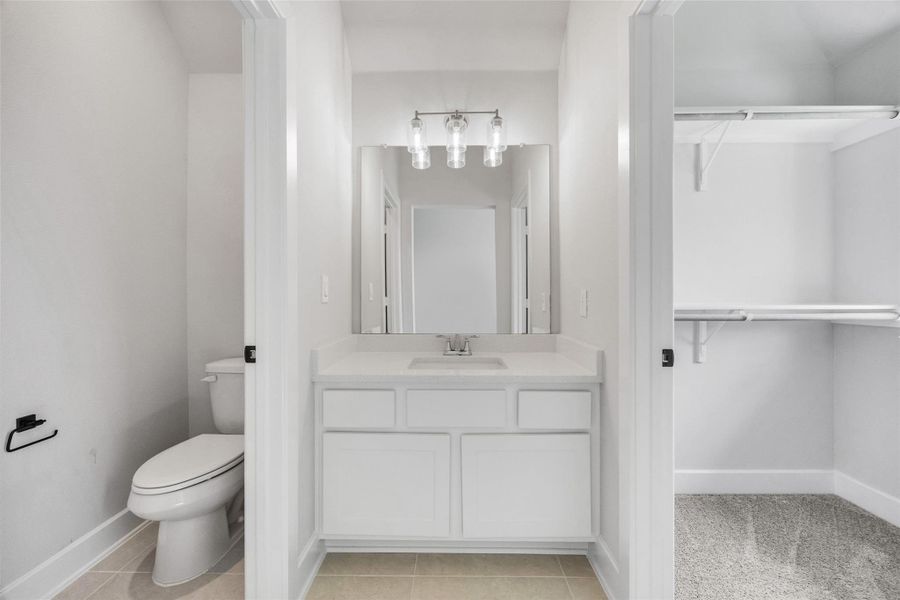 Bathroom with vanity, light tile patterned floors, and a walk in closet Bathroom with vanity, light tile patterned floors, and a walk in closet