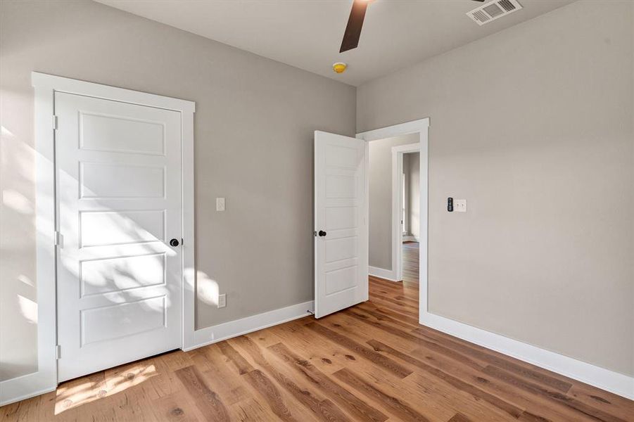 Unfurnished bedroom featuring wood finished floors and a ceiling fan Unfurnished bedroom featuring wood finished floors and a ceiling fan