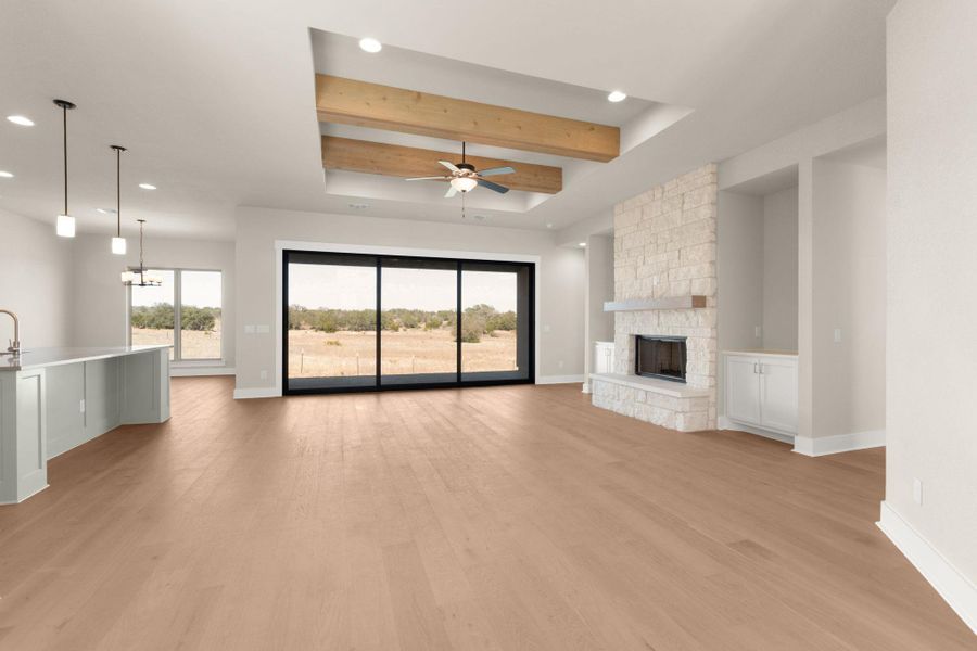 Unfurnished living room featuring a raised ceiling, recessed lighting, ceiling fan, light wood finished floors, and a fireplace