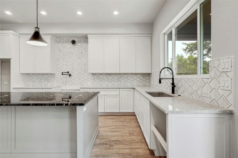 Kitchen featuring white cabinets, dark stone counters, and a sink