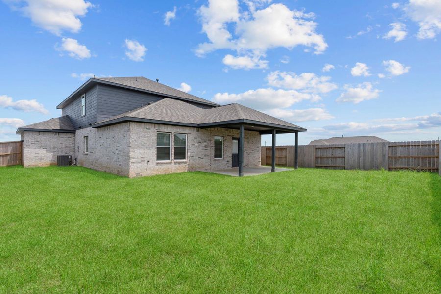 Rear exterior view showcasing the large covered patio and spacious fenced backyard, perfect for outdoor living. Rear exterior view showcasing the large covered patio and spacious fenced backyard, perfect for outdoor living.