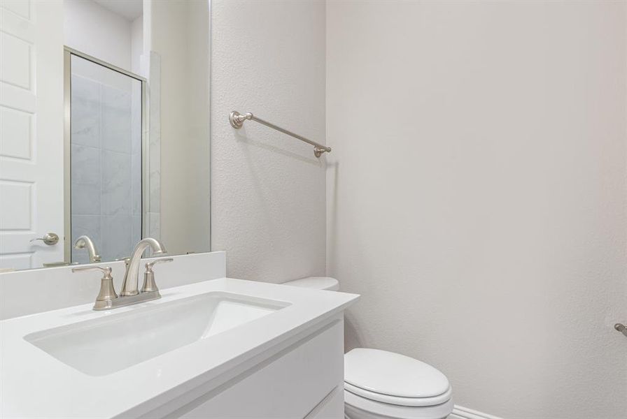 Bathroom featuring a textured wall, vanity, and a shower stall