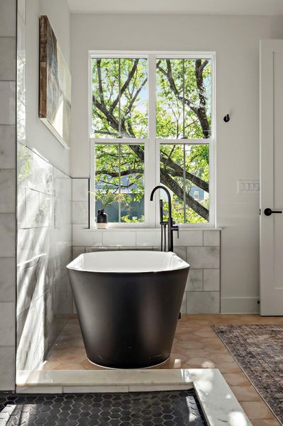 Full bath featuring a freestanding tub, healthy amount of natural light, tile walls, and a sink