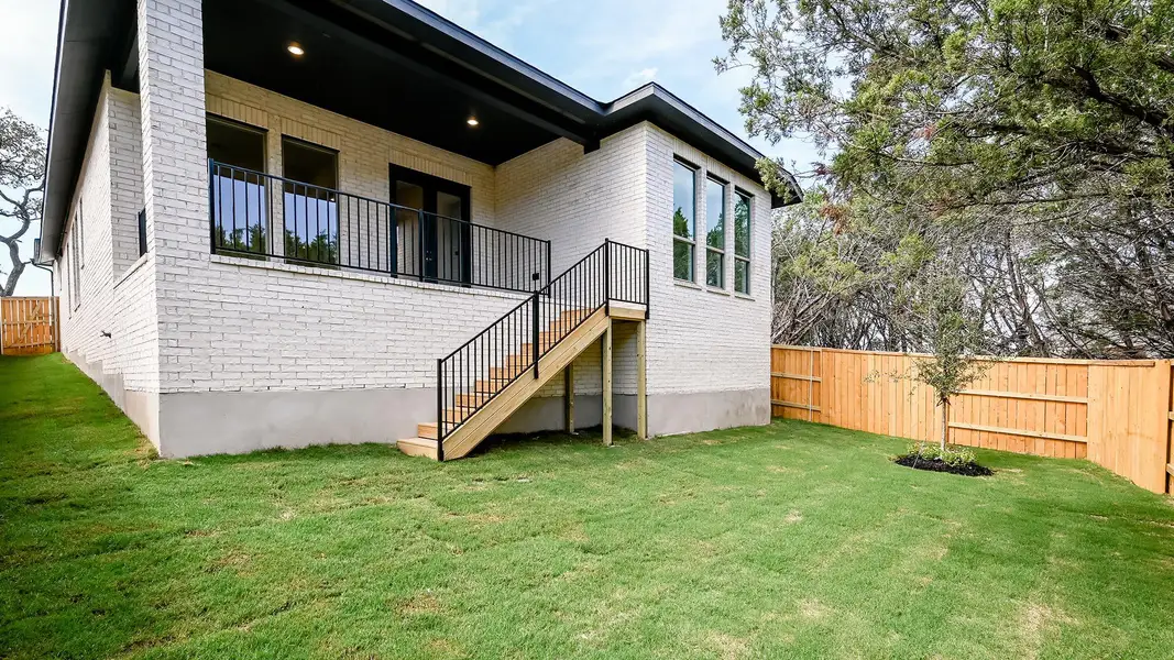 Back of house with brick siding, a fenced backyard, and stairs