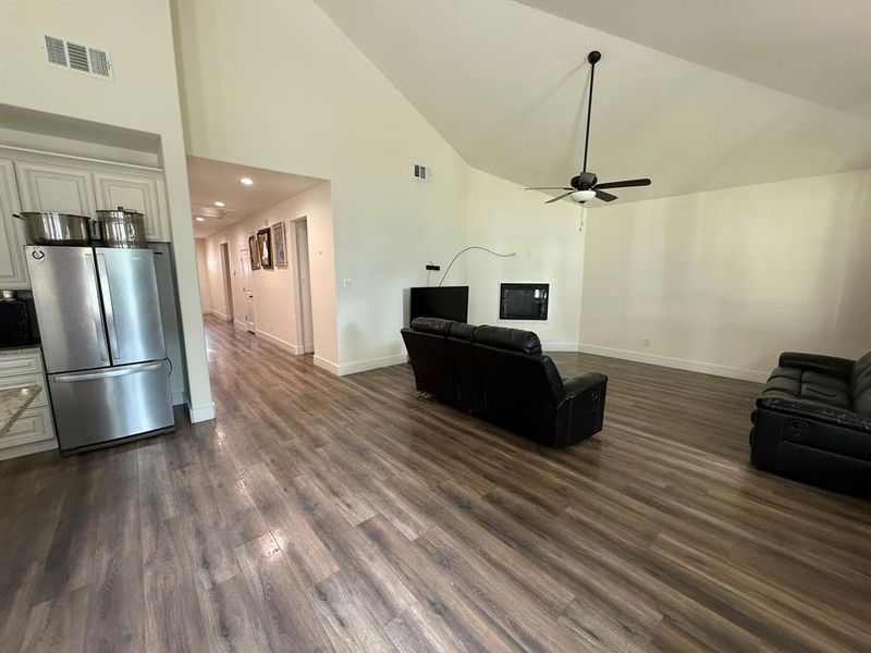 Living room with a ceiling fan, high vaulted ceiling, dark wood-type flooring, and recessed lighting