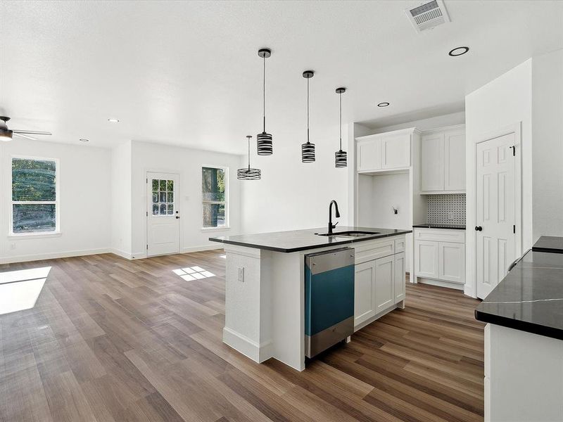 Kitchen featuring white cabinetry, hardwood / wood-style flooring, sink, and an island with sink