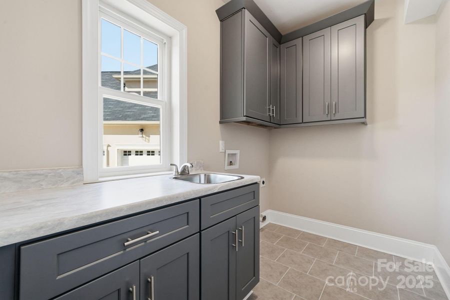 Spacious laundry/mud-room showing upgraded cabinetry and built-in sink. Spacious laundry/mud-room showing upgraded cabinetry and built-in sink.