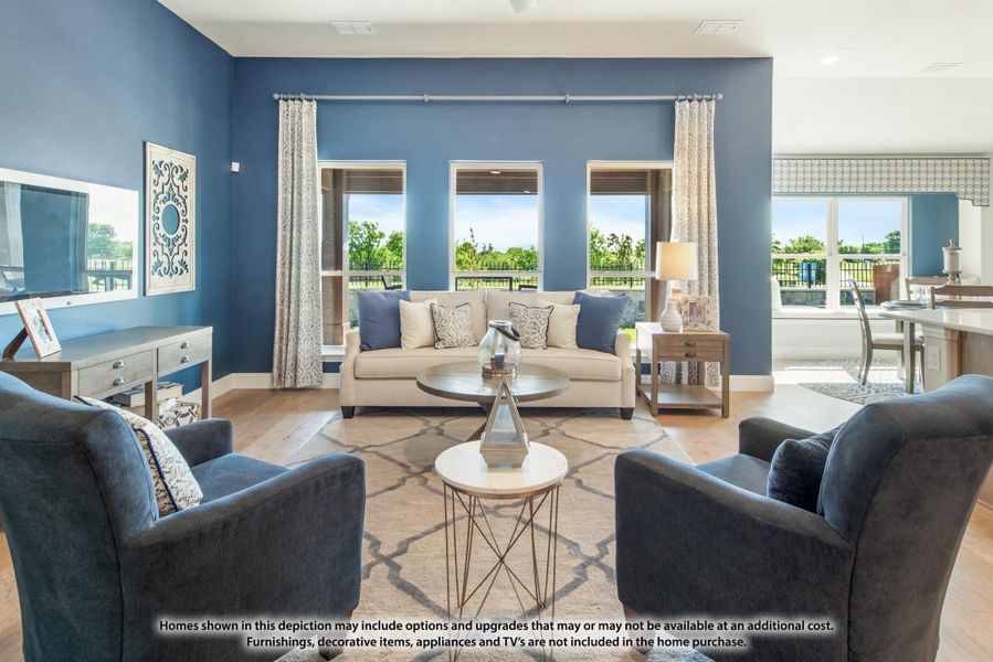 Living room with blue accent walls, beige sofa, gray armchairs, and large windows with outdoor views Living room with blue accent walls, beige sofa, gray armchairs, and large windows with outdoor views