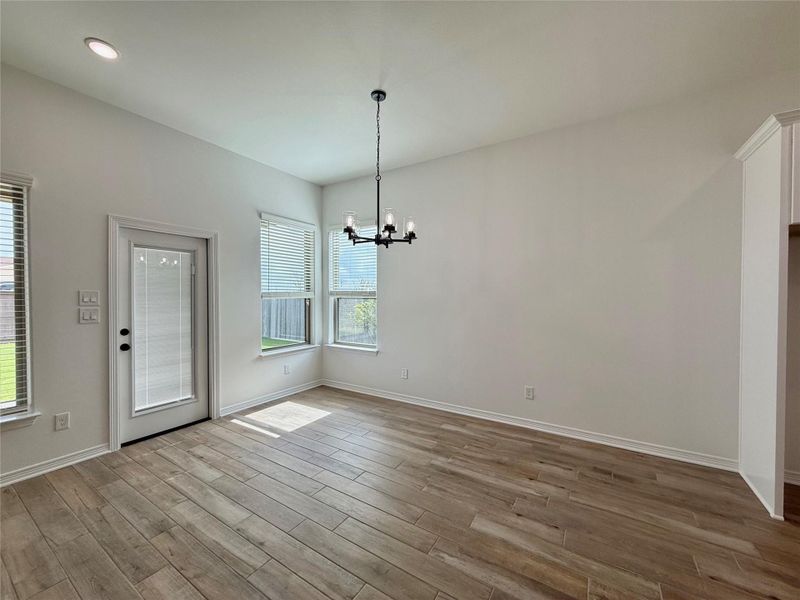 Spacious room featuring wood-finish tile flooring, recessed lighting, and a contemporary chandelier