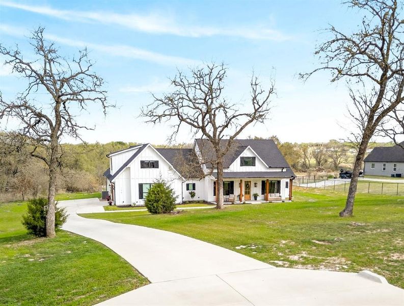 Modern farmhouse style home featuring a porch, board and batten siding, a front lawn, and driveway Modern farmhouse style home featuring a porch, board and batten siding, a front lawn, and driveway