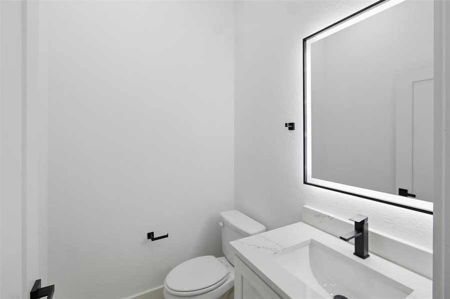 Half bathroom featuring vanity and a textured wall