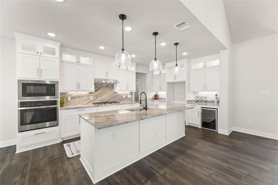 Kitchen with glass insert cabinets, decorative backsplash, light stone counters, stainless steel appliances, and recessed lighting Kitchen with glass insert cabinets, decorative backsplash, light stone counters, stainless steel appliances, and recessed lighting