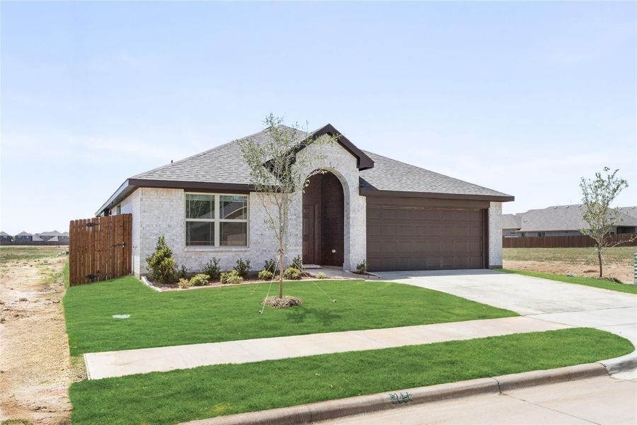 Single-story home with white brick exterior, arched entry, two-car garage, and green front lawn