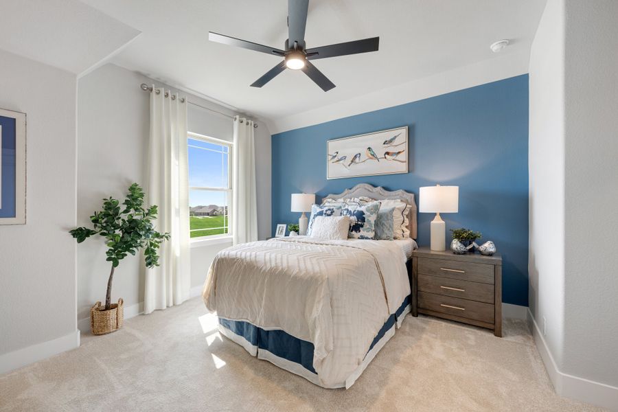 Bedroom with blue accent wall, ceiling fan, carpet flooring, and large window with natural light