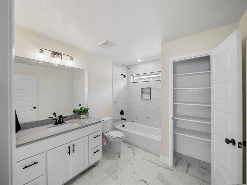 Full bathroom featuring toilet, tiled shower / bath combo, and vanity