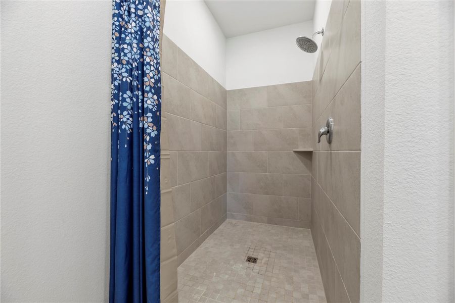Walk-in shower with tile surround.