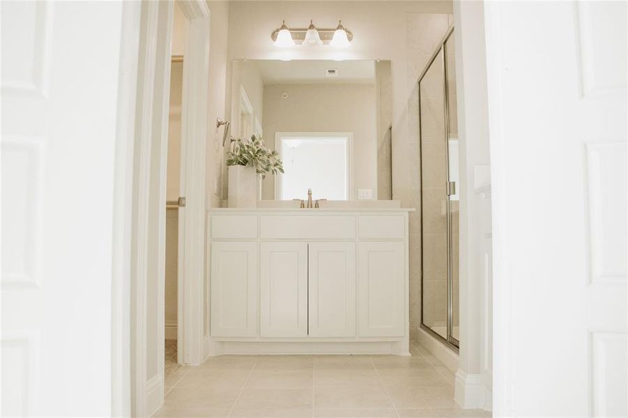 Bathroom with a shower with door, vanity, and tile patterned floors