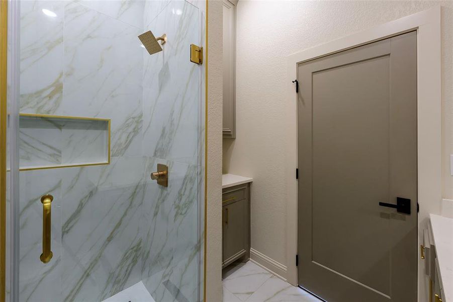 Full bathroom with vanity, a marble finish shower, and light marble finish floors