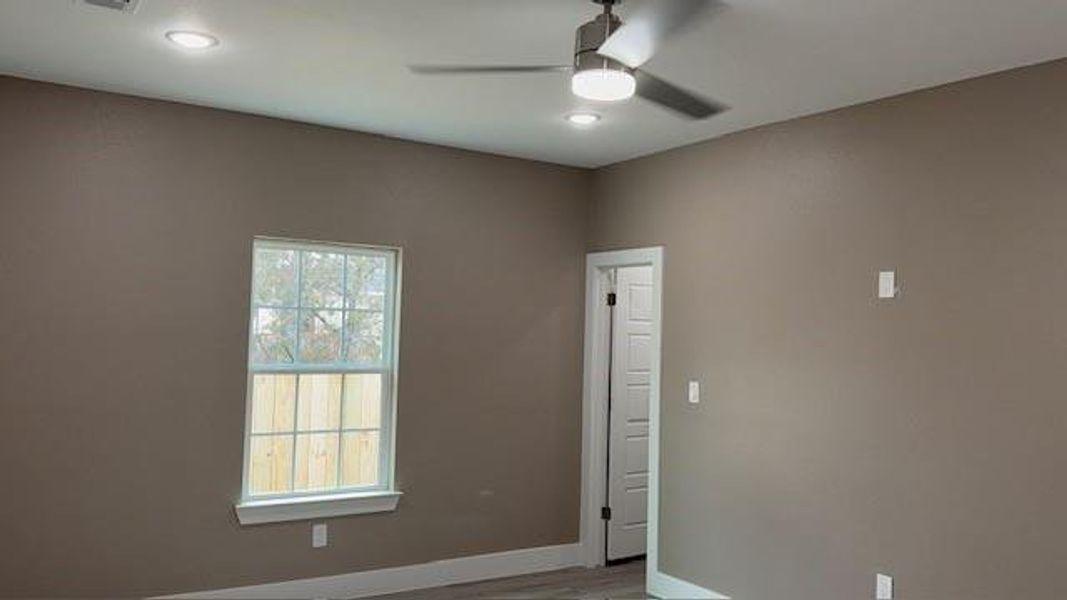 Empty room with ceiling fan, baseboards, wood finished floors, and recessed lighting Empty room with ceiling fan, baseboards, wood finished floors, and recessed lighting