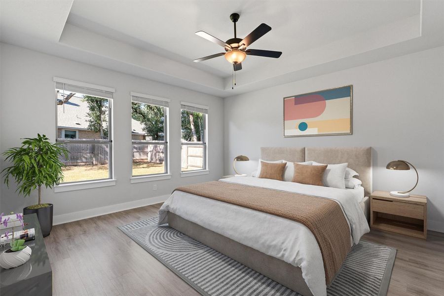 Bedroom featuring a tray ceiling, wood finished floors, and a ceiling fan