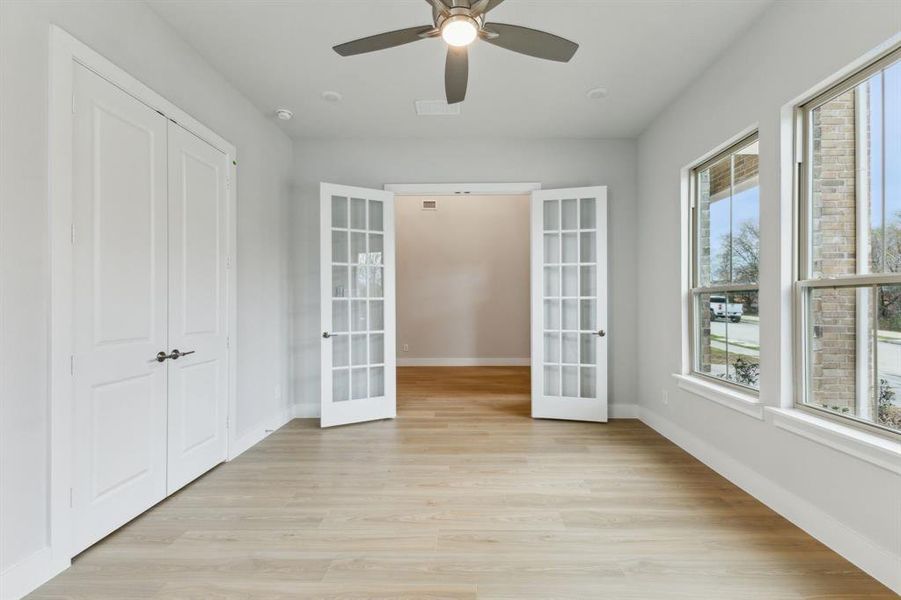 Spare room with french doors, light wood-style floors, and ceiling fan