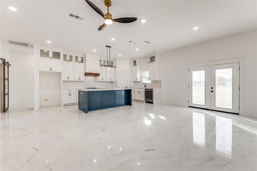 Kitchen featuring ceiling fan, a center island, pendant lighting, white cabinets, and custom range hood