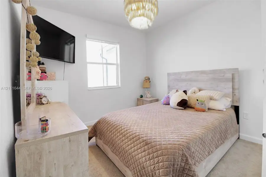 Neutral-toned interior space featuring wall-to-wall carpeting, a single-hung window, and a ceiling-mounted light fixture Neutral-toned interior space featuring wall-to-wall carpeting, a single-hung window, and a ceiling-mounted light fixture