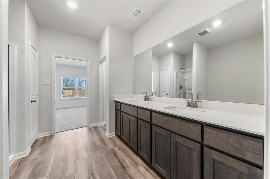 Bathroom featuring wood finished floors, a stall shower, a sink, and visible vents