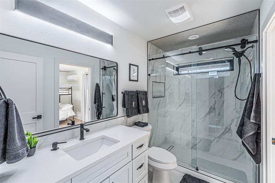 Ensuite bathroom featuring vanity and a marble finish shower