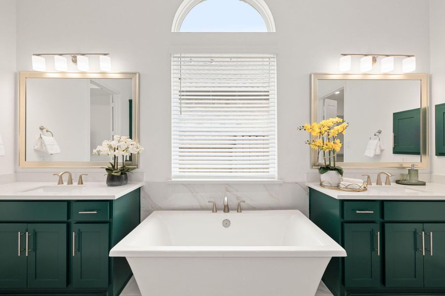 Luxurious primary bath featuring a soaking tub, dual vanities, and a bright, polished design.
