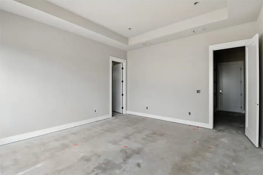 Unfurnished bedroom featuring a raised ceiling and concrete floors Unfurnished bedroom featuring a raised ceiling and concrete floors