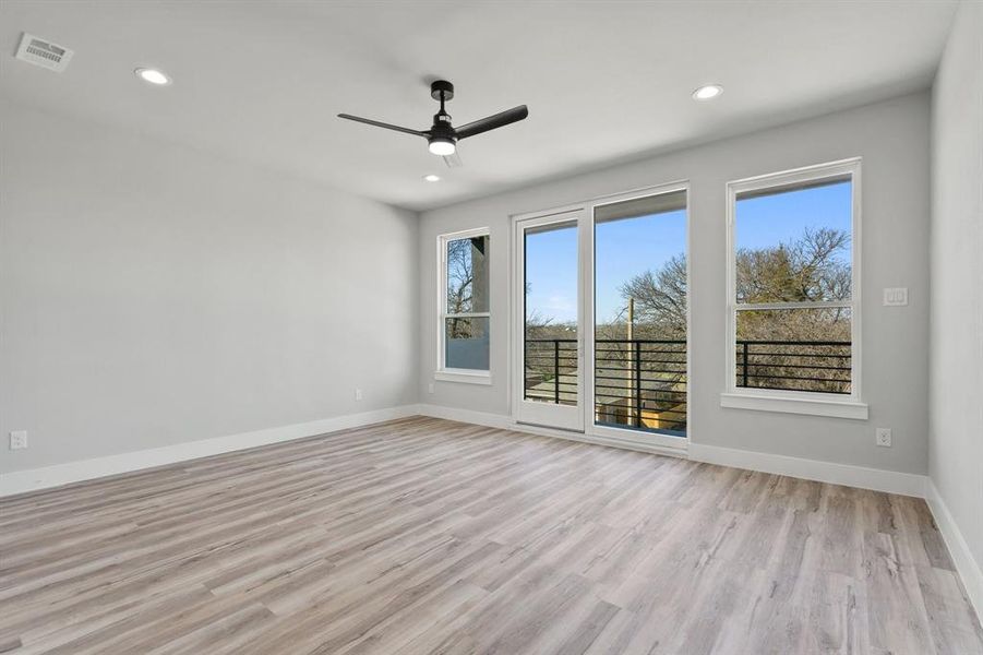 Empty room with a wealth of natural light, ceiling fan, and light wood-type flooring