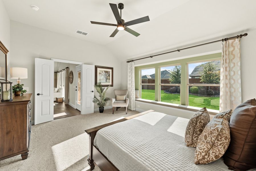 Spacious master bedroom with ceiling fan, large windows, carpet flooring, and wood dresser