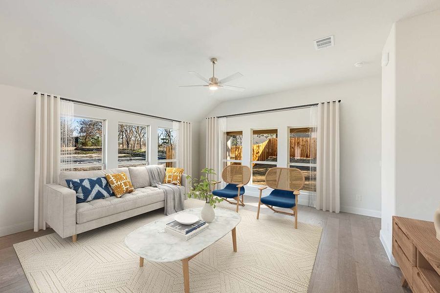 Living room with vaulted ceiling, ceiling fan, gray sofa, and hardwood floors with large windows