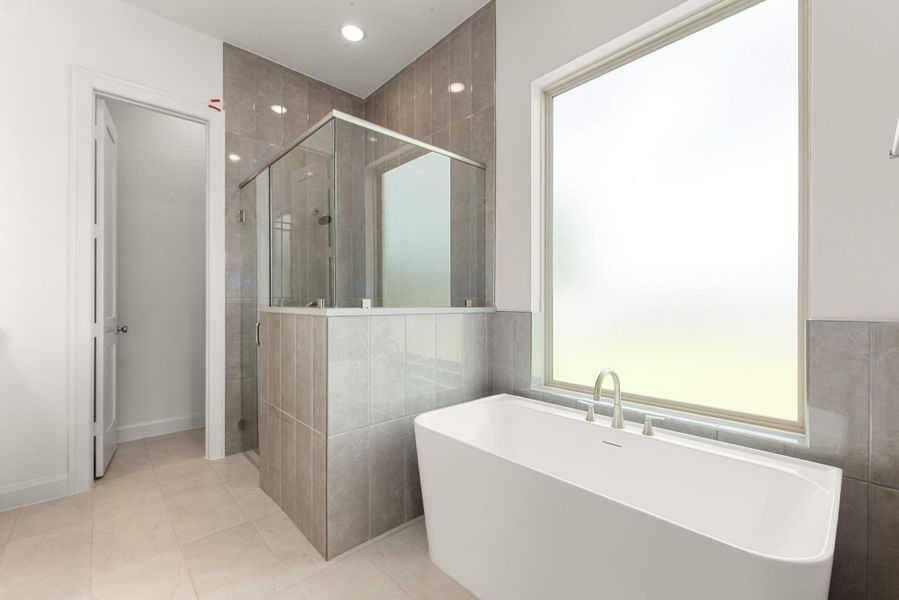 The primary bath includes a freestanding soaking tub and a fully enclosed glass shower, both finished in large-format tile that carries a soft, spa-like feel through the whole room. The primary bath includes a freestanding soaking tub and a fully enclosed glass shower, both finished in large-format tile that carries a soft, spa-like feel through the whole room.
