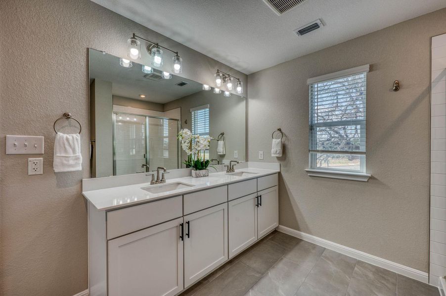 Double vanity highlights this clean bath with tile flooring and natural light. Double vanity highlights this clean bath with tile flooring and natural light.