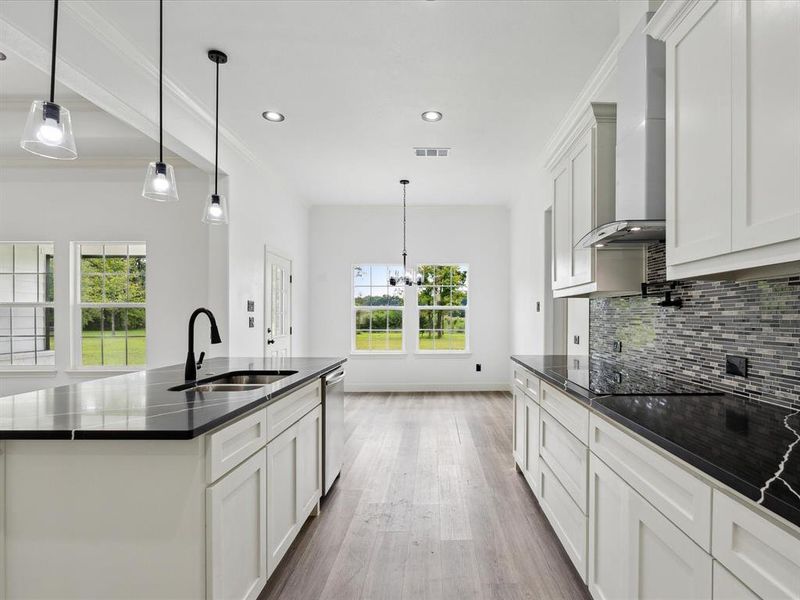 Kitchen with tasteful backsplash, a kitchen island with sink, light hardwood / wood-style floors, sink, and wall chimney exhaust hood