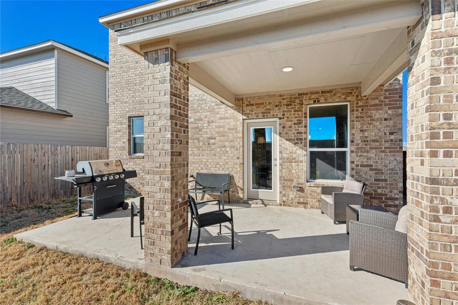 Enjoy outdoor living on the charming brick patio with an extended covered porch that offers added privacy and overlooks the fully fenced backyard. The inviting patio/terrace also includes a dedicated grilling area—perfect for relaxing or entertaining.