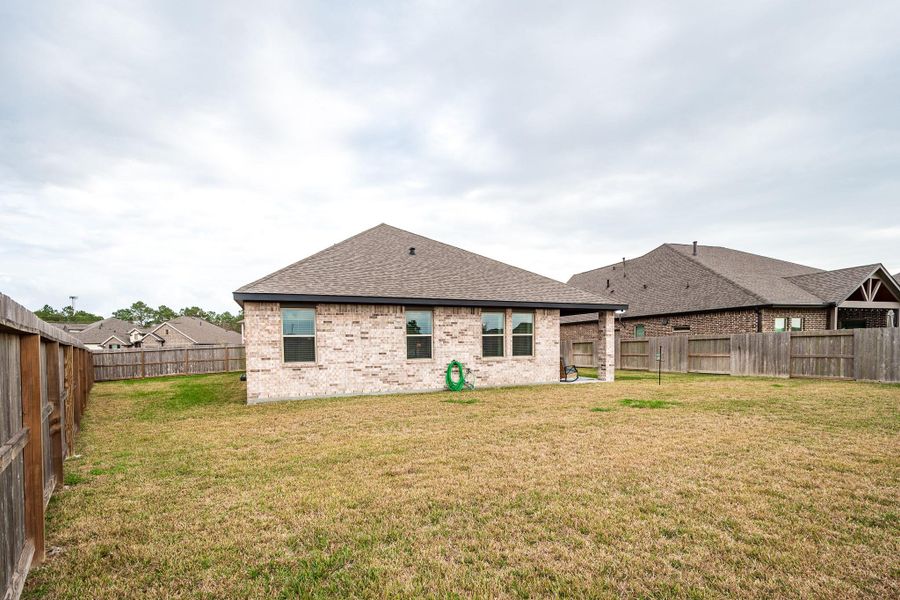 This photo shows a brick home with a fenced backyard, offering a spacious lawn ideal for outdoor activities. The roof is gabled, and there are neighboring houses visible, suggesting a suburban setting. This photo shows a brick home with a fenced backyard, offering a spacious lawn ideal for outdoor activities. The roof is gabled, and there are neighboring houses visible, suggesting a suburban setting.