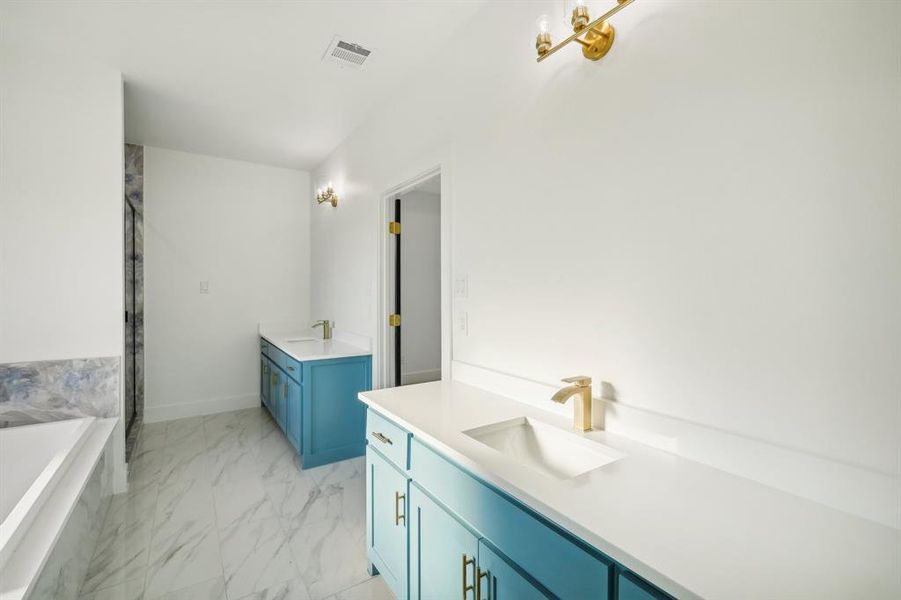 Full bathroom featuring two vanities, a bathtub, light marble finish floors, and a shower stall Full bathroom featuring two vanities, a bathtub, light marble finish floors, and a shower stall