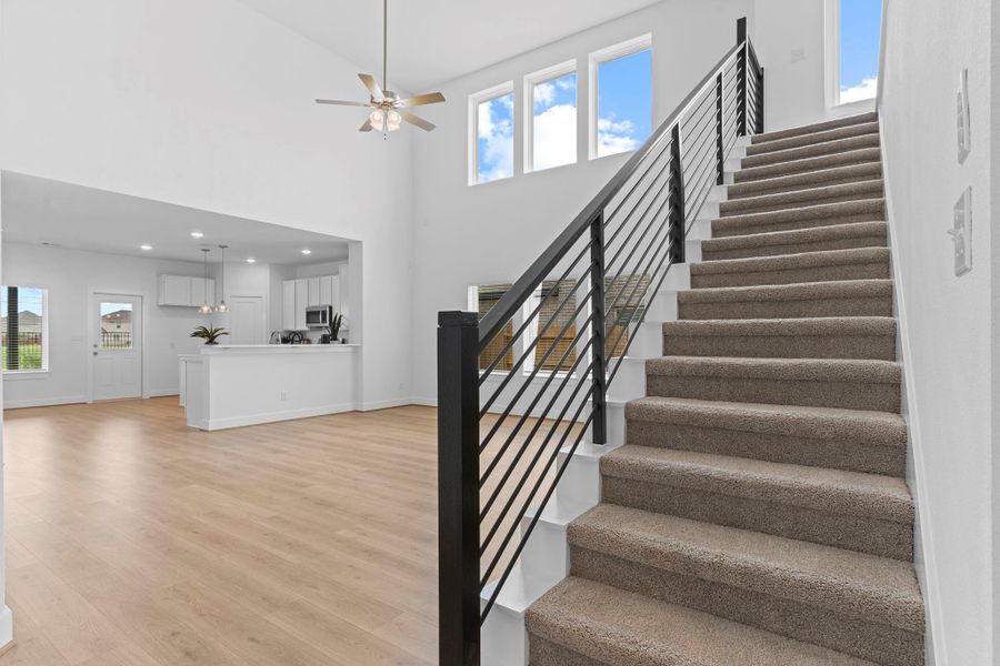 Talk about a showstopper! The dramatic two-story family room is complemented by soaring ceilings, expansive windows, and a sleek modern staircase that adds architectural flair. **Image Representative of Plan Only and May Vary as Built**.