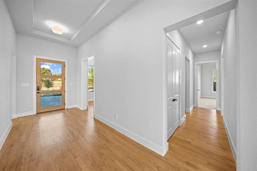 Entryway with light wood finished floors and a tray ceiling Entryway with light wood finished floors and a tray ceiling
