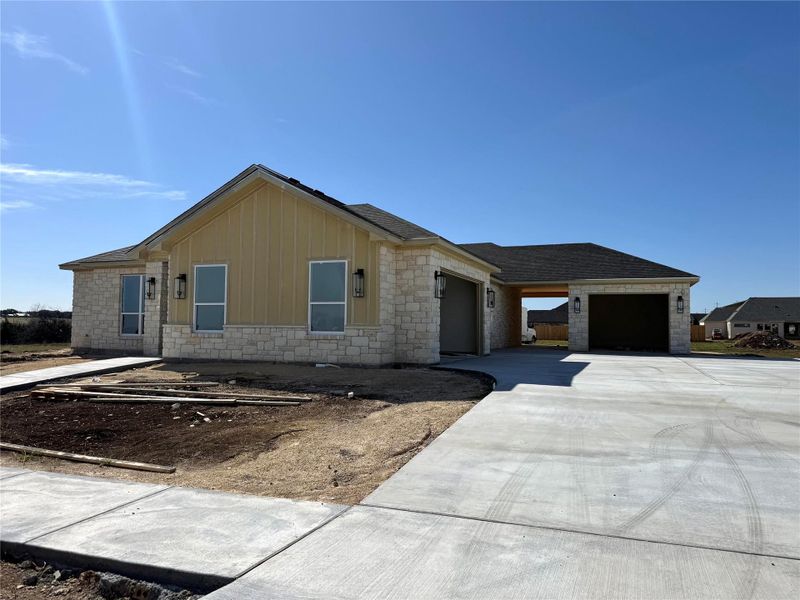 Ranch-style home featuring a garage, stone siding, board and batten siding, and driveway