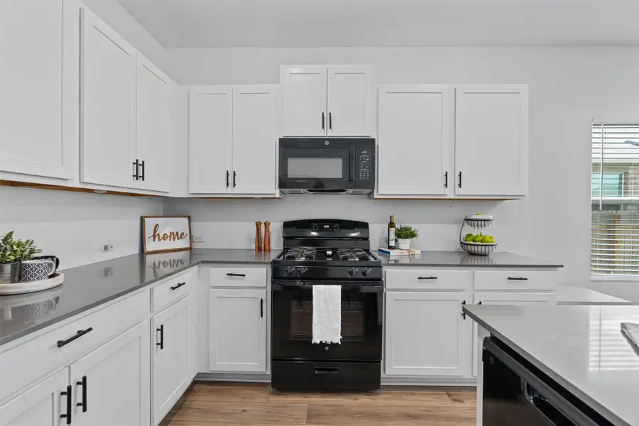 Kitchen featuring black appliances, white cabinetry, and light wood-style flooring
