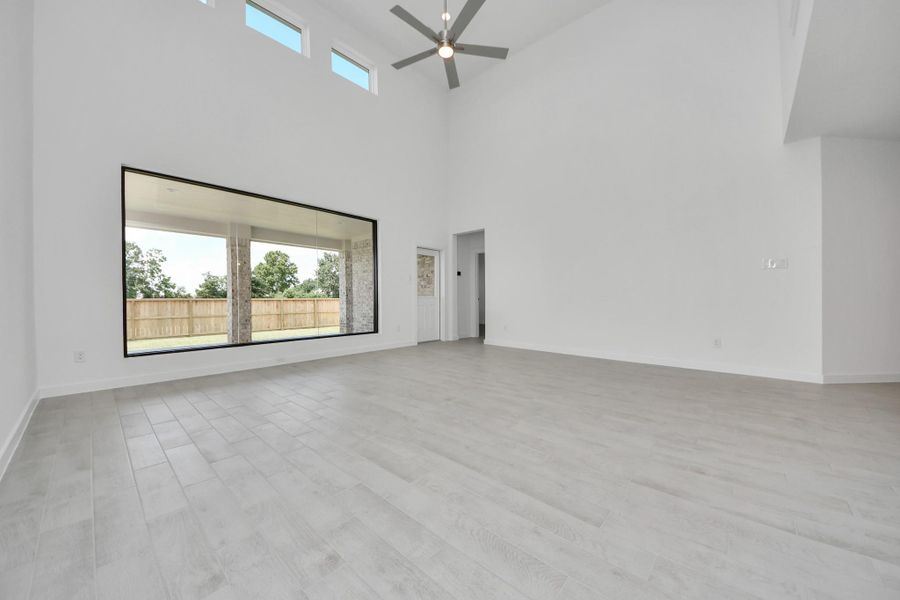 Welcome family and guests to your charming living room! With its high ceilings, recessed lighting, ceiling fan, custom paint, beautiful flooring, and large windows that let in abundant natural light, this room is perfect for gatherings.