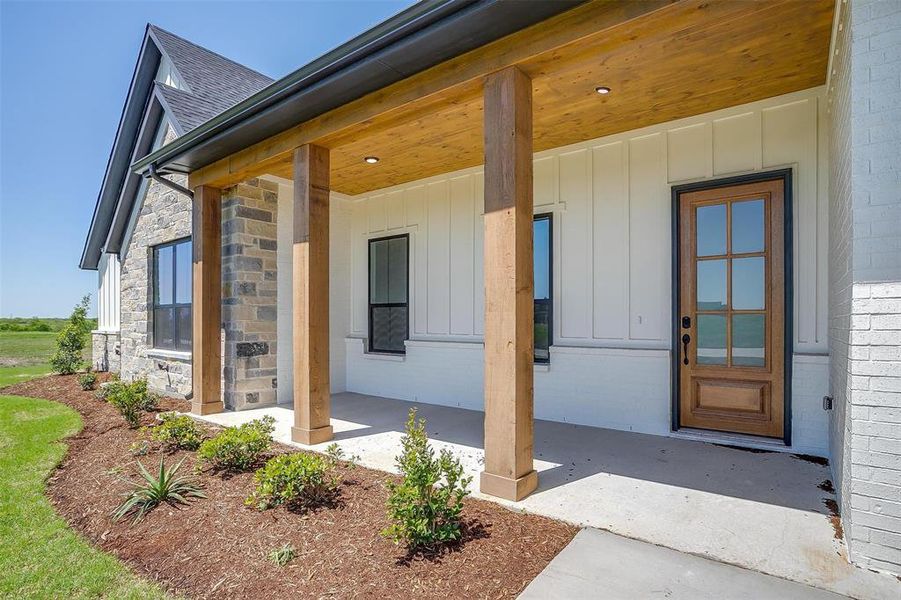 Entrance to property with a porch, roof with shingles, and board and batten siding