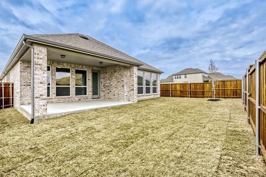 Rear view of property with a fenced backyard, roof with shingles, brick siding, and a patio area