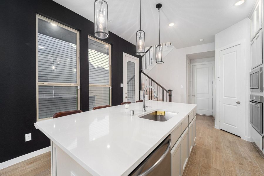 Bright, modern kitchen with quartz counters, artisan lighting, and stylish backsplash.
