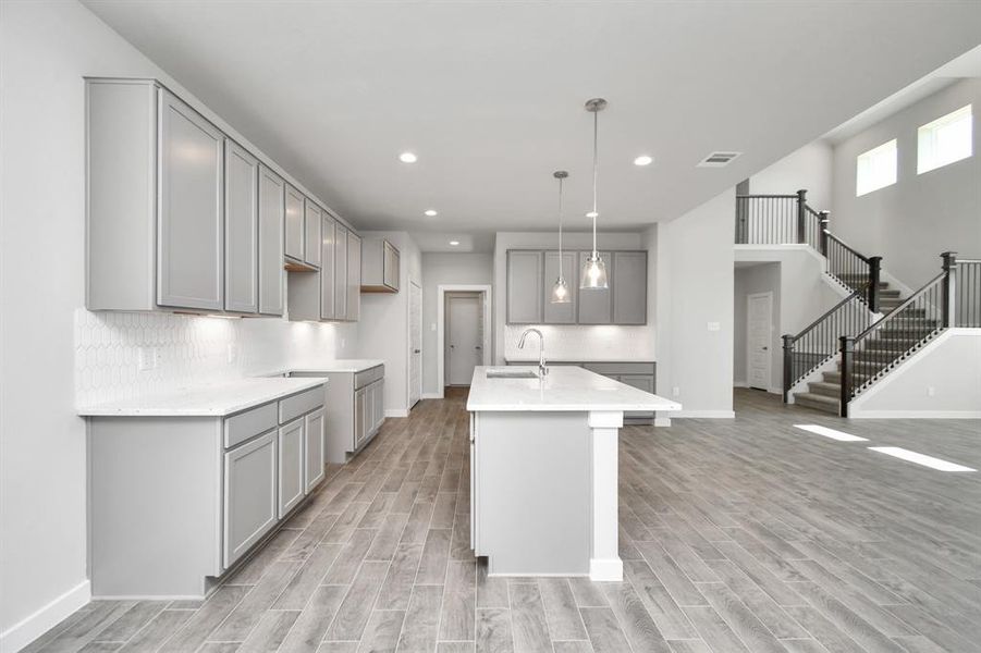 The kitchen is a culinary haven, featuring granite countertops, a tile backsplash, stainless steel appliances, 42” upper cabinets, and undercabinet lighting. Sample photo of completed home with similar floor plan. As-built interior colors and selections may vary.