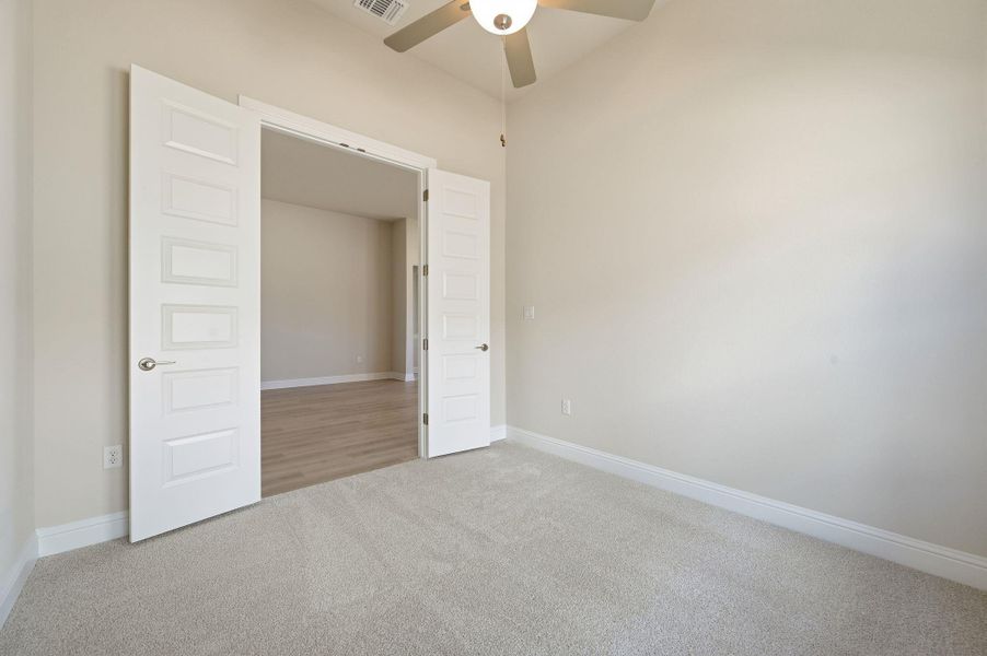Unfurnished bedroom featuring light carpet and a ceiling fan Unfurnished bedroom featuring light carpet and a ceiling fan
